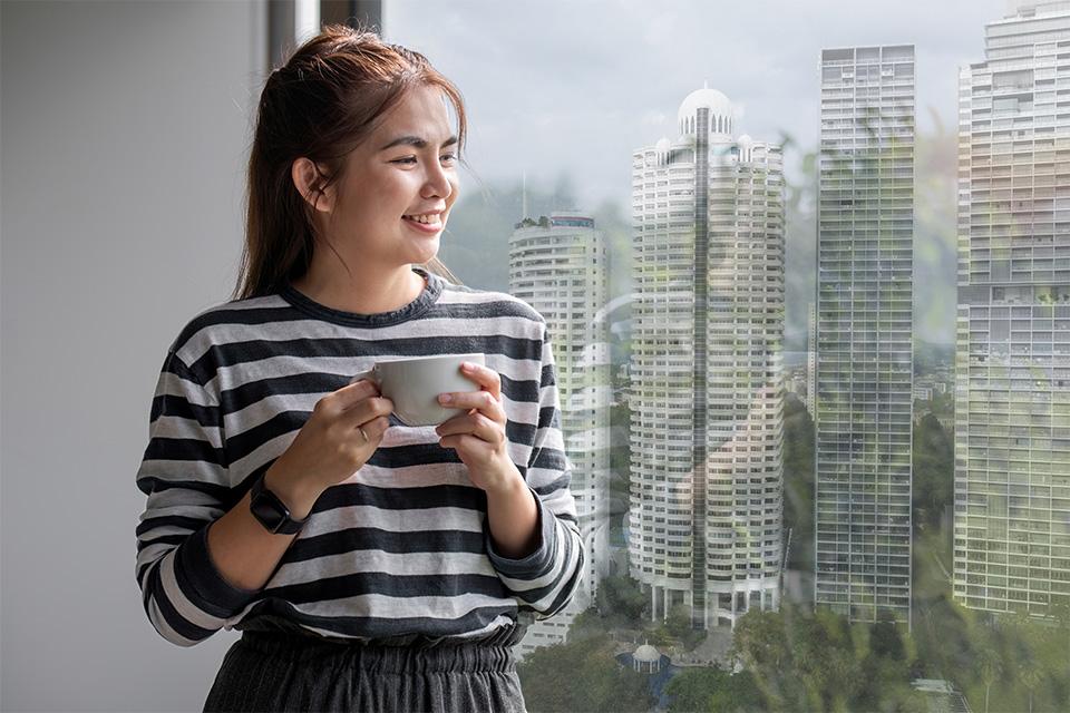 Womenstanding and  looking out of a high rise building in a Singapore property