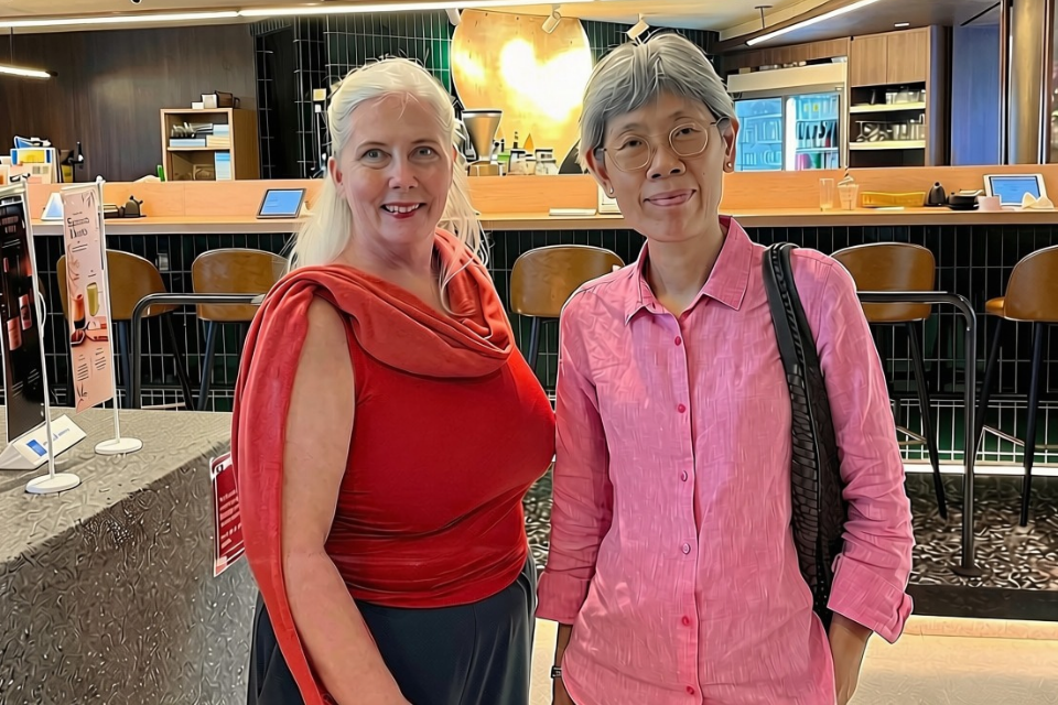 Writer and friend wearing red and pink at Sun with Moon with the gold sun reflection above the kaunta-seki counter seating