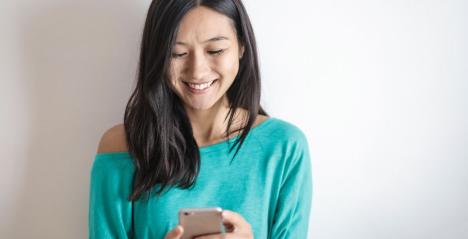 Girl wearing a Green Jumper holding a mobile phone