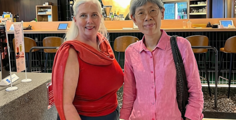 Writer and friend wearing red and pink at Sun with Moon with the gold sun reflection above the kaunta-seki counter seating
